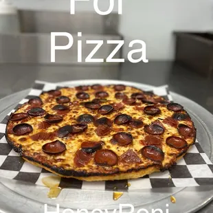 a pepperoni pizza on a checkered plate