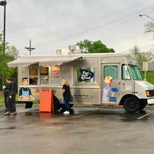 a couple of people standing in front of a food truck