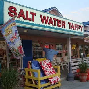 a man standing in front of a salt water taffy store