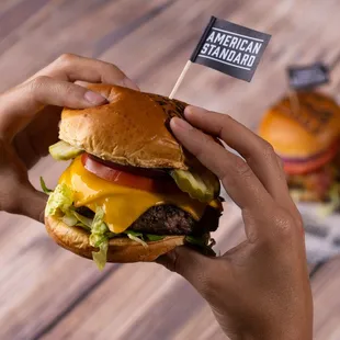 a hand holding a cheeseburger