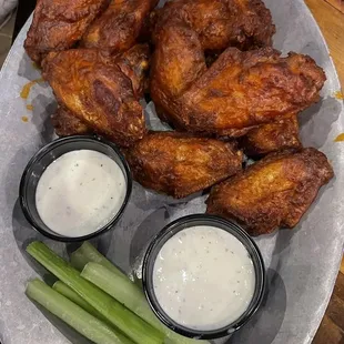 a plate of chicken wings, celery, and ranch dressing