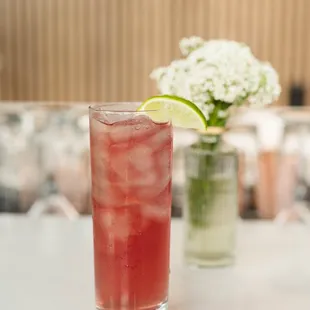 a glass of watermelon and a vase of flowers