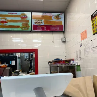 a restaurant counter with a menu on the wall