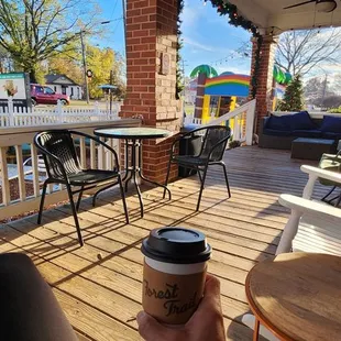 a porch with chairs, tables, and a cup of coffee