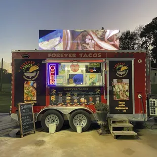 The food truck has pictures of the food (some prices) and an advertising screen on the roof.