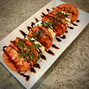 a plate of sliced tomatoes with sauce