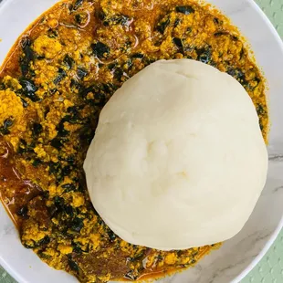 a bowl of stew with a ball of bread