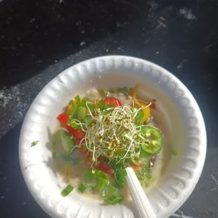 a bowl of soup with vegetables and sprouts