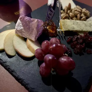 a cheese board with grapes, cheese, and nuts