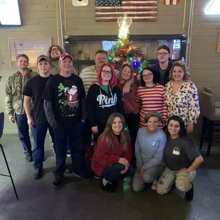 a group of people posing in front of a christmas tree