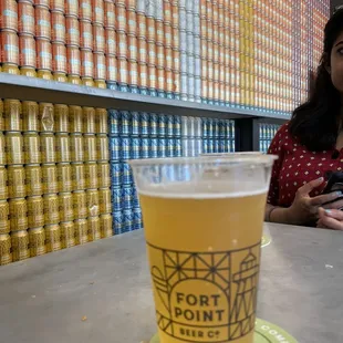 a woman sitting at a table with a cup of beer