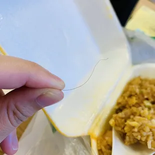 a person's hand holding a spoon over a bowl of rice