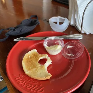 a half eaten bagel on a red plate