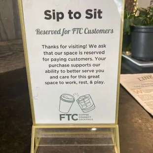 a sign stating customers to sip to sit