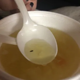 a person holding a spoon over a bowl of soup