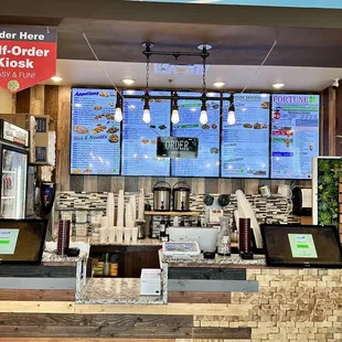a restaurant counter with a menu on the wall