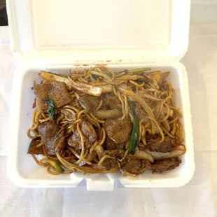 a take out box of noodles and beef