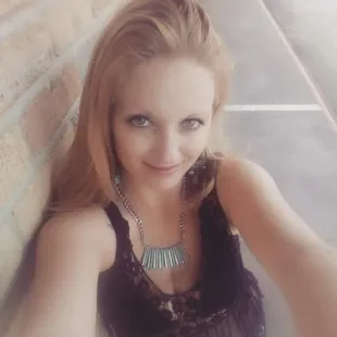 a woman leaning against a brick wall