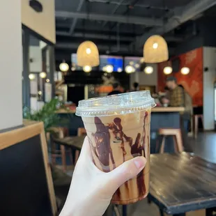 a hand holding a cup of iced coffee