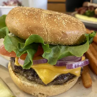 a cheeseburger with lettuce, tomato, onion, and pickle
