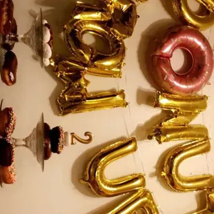 a donut and balloons on a wall