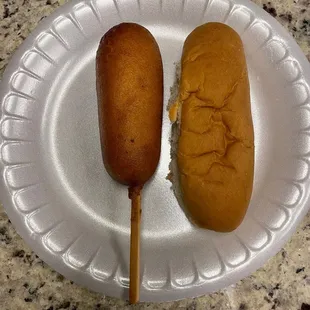 Corn dog next to a normal sized bun