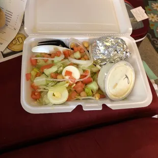 a takeout container with salad and dressing