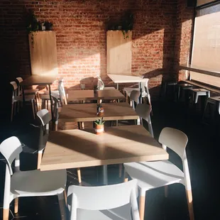 tables and chairs in a room with a brick wall