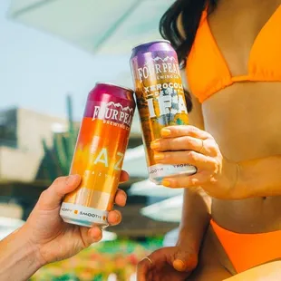 a woman in a bikini holding two cans of beer