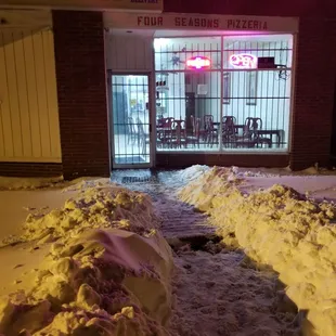 snow piled up in front of a pizzeria restaurant
