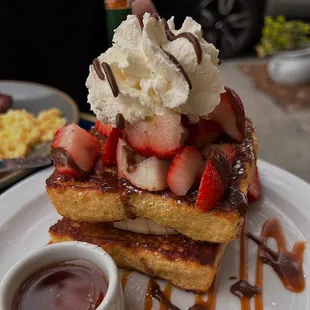 a stack of french toast with whipped cream and strawberries