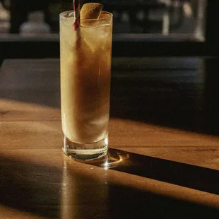 a tall glass with a drink on a table