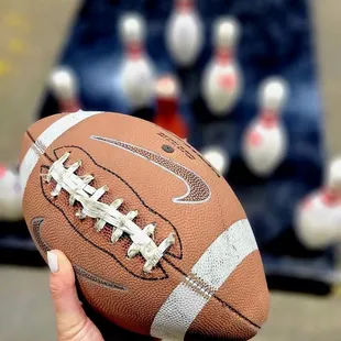 a person holding a football in front of bowling pins