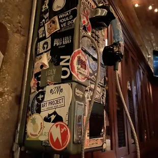 an old pay phone covered in stickers