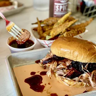 Pulled pork sandwich, fried okra and a bratwurst being dunked