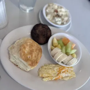 Scrambled egg, fruit, biscuit, sausage, and gravy.
