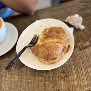 a croissant sandwich and a cup of coffee