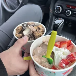 a person holding a cup of ice cream and strawberries