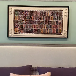 Framed piece above the bed