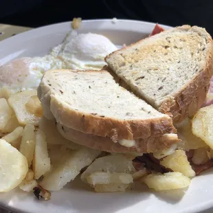 Ham breakfast with eggs over easy, breakfast potatoes and toast.