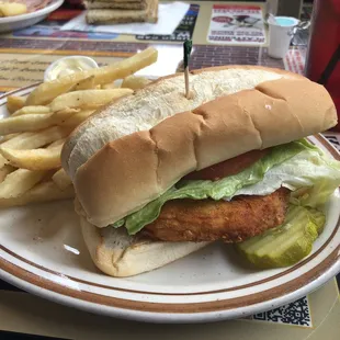 Chicken patty on hoagie bun with lettuce, tomato and fries.