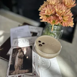 a glass of coffee and a flower on a table