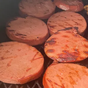 a bunch of hot dogs cooking on a grill