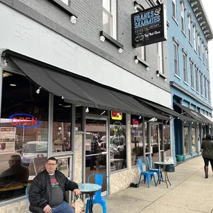 a man sitting on a bench in front of a restaurant