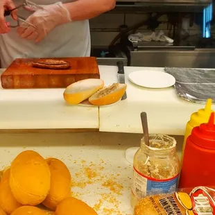 a person preparing hot dogs