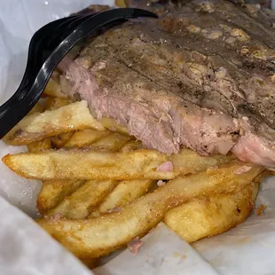 a steak and french fries in a container