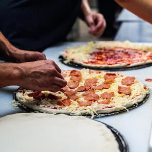 two pizzas being prepared