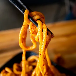 a close up of noodles being held by chopsticks