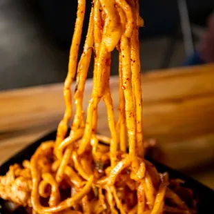 noodles being lifted by chopsticks