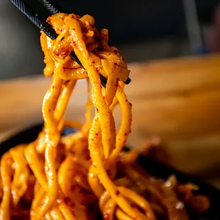 a close up of noodles being lifted by chopsticks